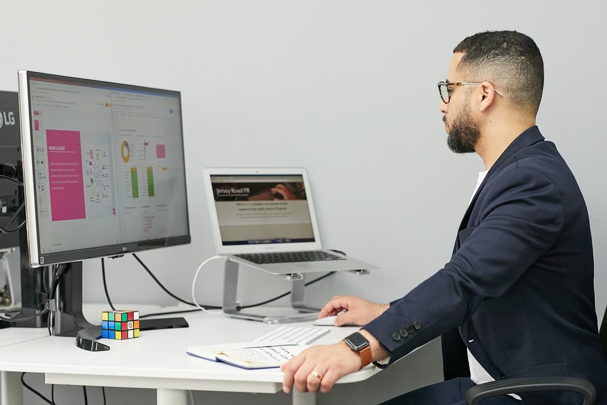 Hombre sentado en un escritorio con laptop y computadora